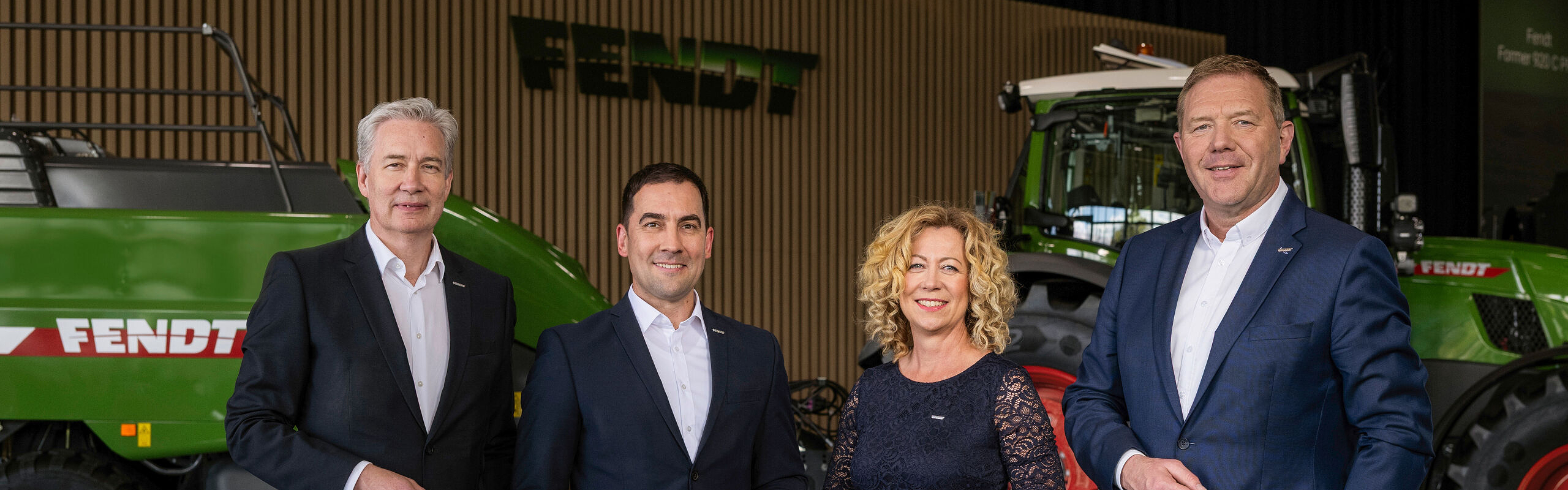 Von links nach rechts stehen die Geschäftsführer Ekkehart Gläser, Dr. Josef Mayer, Ingrid Bußjäger-Martin und Christoph Gröblinghoff nebeneinander im Fendt Forum vor einem Fendt Traktor und der Fendt Quaderballenpresse