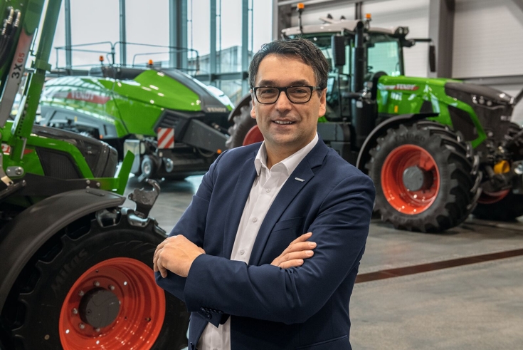 Roland Schmidt, Vice President Fendt Marketing Roland Schmidt, Vice President Fendt Marketing in einer Halle, im Hintergrund grüne Fendt Traktoren und eine Quaderballenpresse