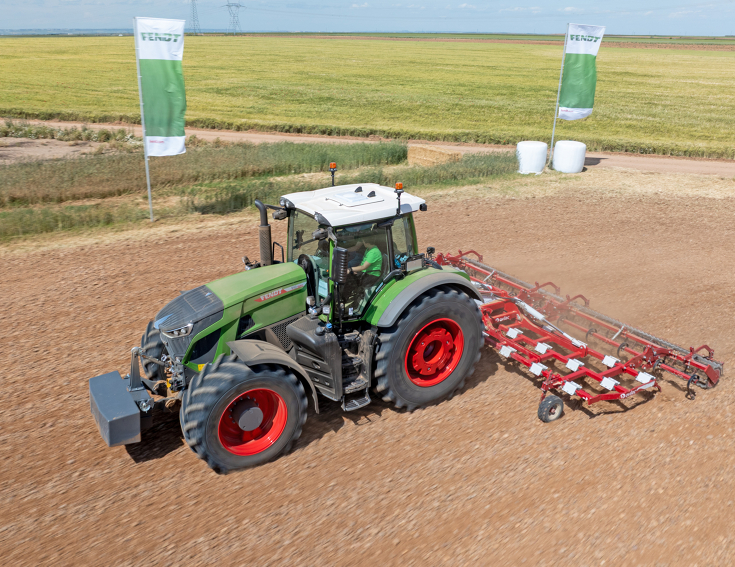 der Fendt 942 Vario mit Ovlac-Grubber und Walze ein grüner Fendt 942 Vario mit Ovlac-Grubber und Walze auf einem Feld im Hintergrund zwei Fendt Fahnen