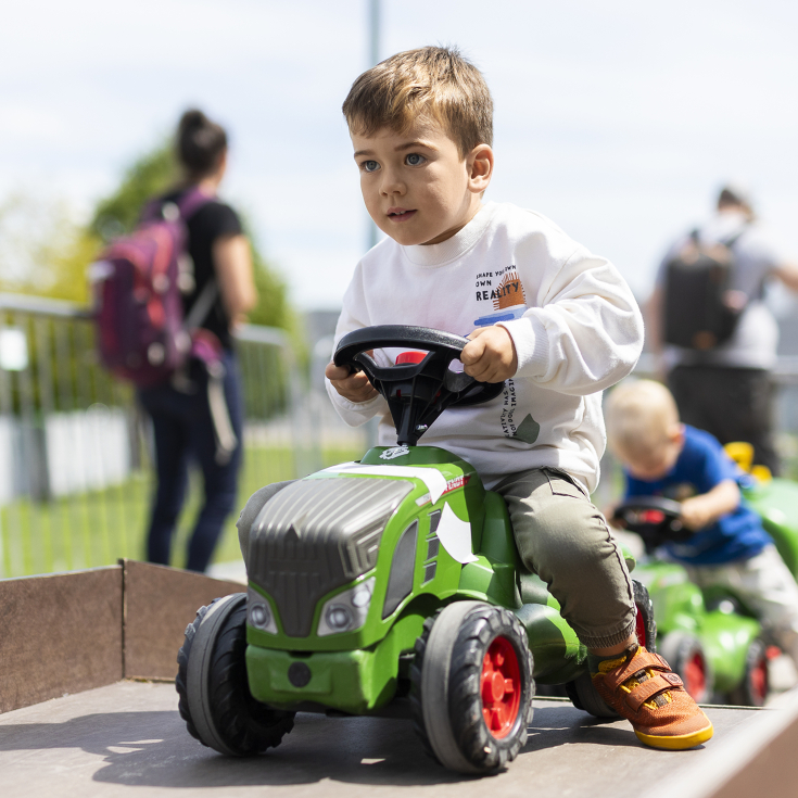 Junge spielt auf einem Fendt-Trettraktor