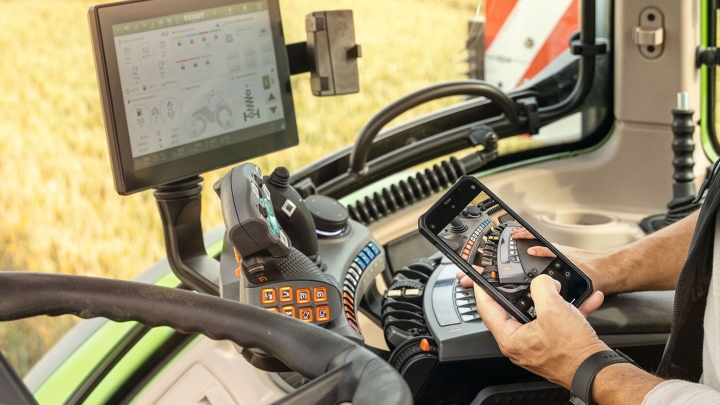 Ein Landwirt sitzt in einem Traktor und schaut auf seinem Handy ein Erklärvideo an.