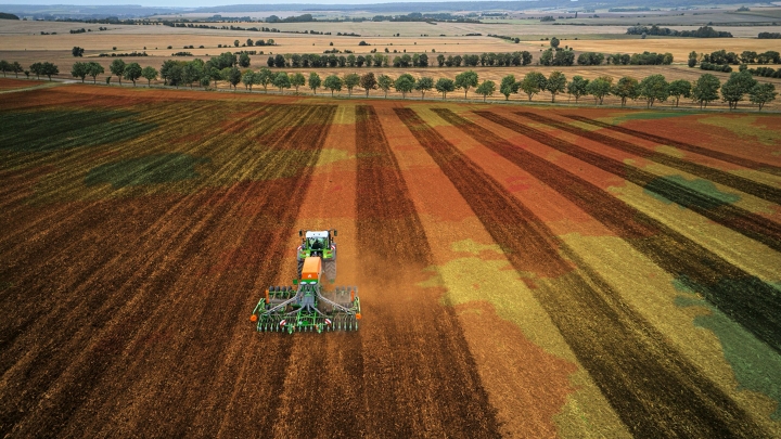 Ein grüner Fendt Traktor mit Anbaugerät bei der präzisen Bodenbearbeitung dank FendtONE Maschinensteuerung