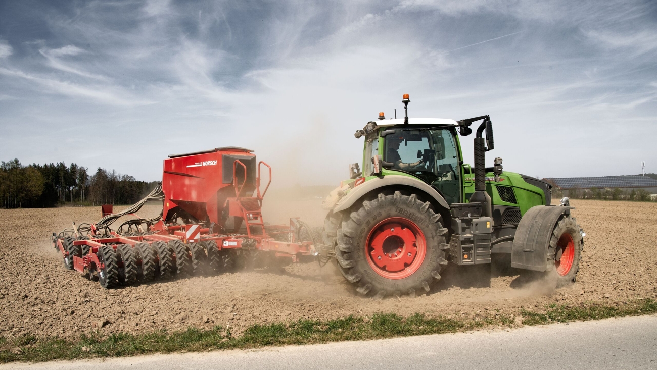 Ein Fendt 700 Vario mit Ladewagen fährt im Sommer auf einer Landstraße