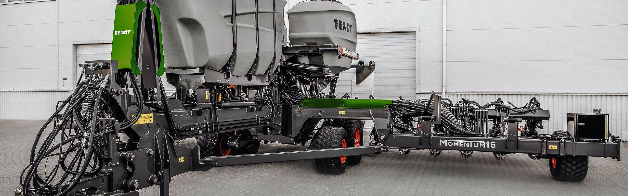 Die Fendt Sämaschine Fendt MOMENTUM steht auf einem Hof vor einer Halle.