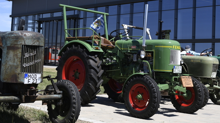 Mehrere Fendt Oldtimer stehen nebeneinandergereiht vor dem Fendt Forum