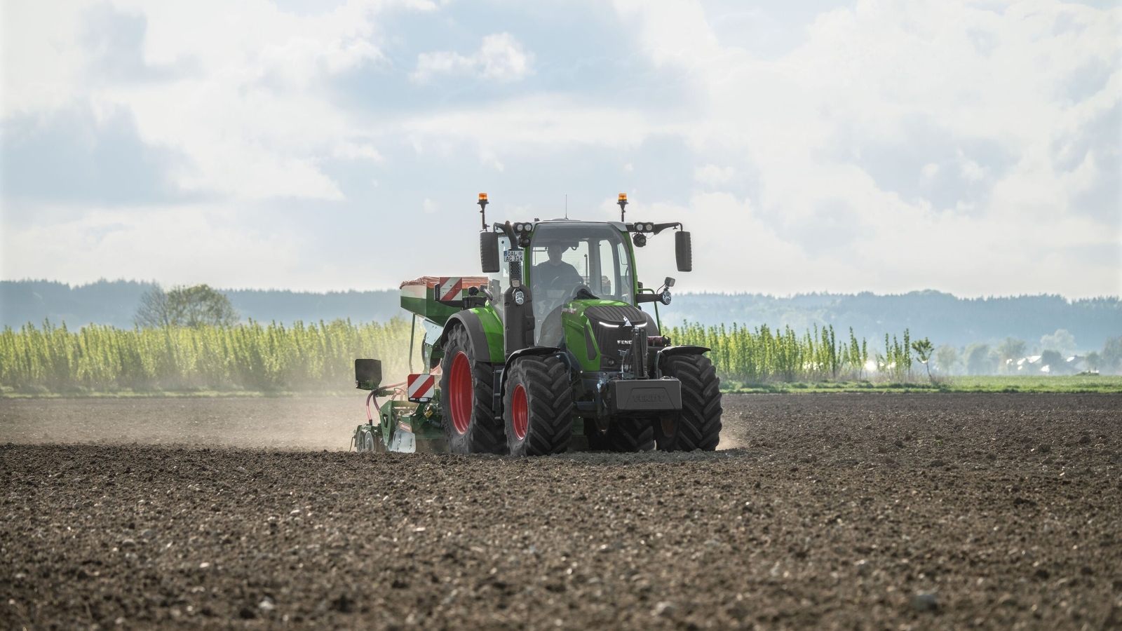 Ein grüner Fendt 300 Vario Gen5 mit roten Felgen im Einsatz auf dem Feld.