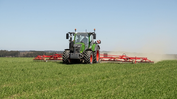 Ein grüner Fendt 300 Vario Gen5 mit roten Felgen im Einsatz auf dem Feld.