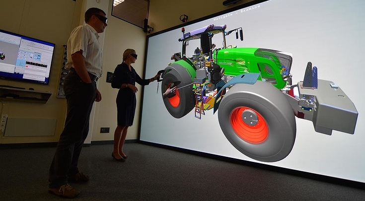 Zwei Fendt Mitarbeiter stehen vor einer großen Leinwand mit einer Traktorgrafik. Sie diskutieren technische Details – ein Moment gelebter Zusammenarbeit und Expertise.