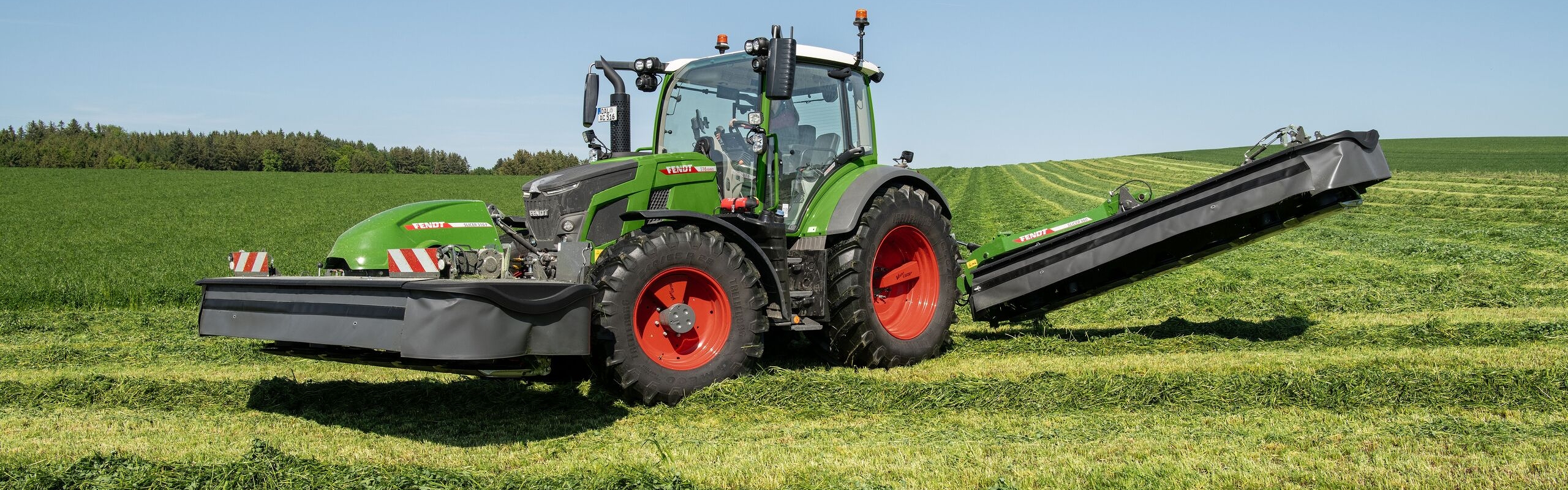 Fendt 500 Vario Gen4 mit Front-Heck-Mähkombination bei der Grünlandpflege auf ebenem Feld