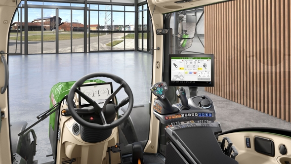 Innenansicht der VisioPlus Kabine eines Fendt 300 Vario Gen5 mit ergonomischem Bedienarm, Lenkrad und großem Terminal vor moderner Hofkulisse mit Glasfront