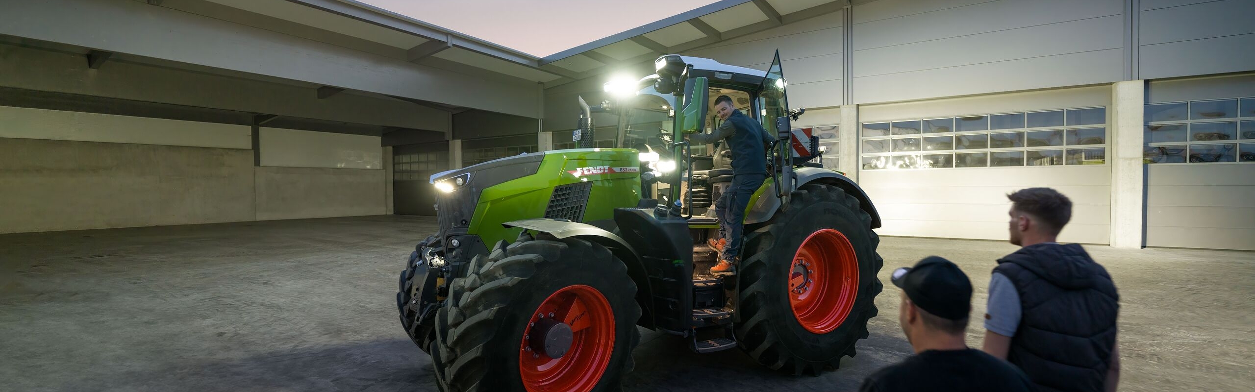 Sicht in den Innenhof eines Lohnunternehmers, der für seine Fahrer den Fendt 800 Vario Traktor mit voller Beleuchtung bereitstehen hat