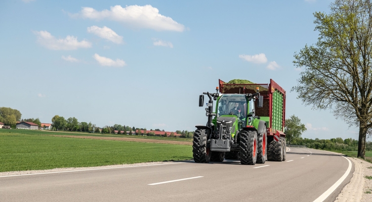 Ein Fendt 500 Vario mit einem Ladewagen im Transport Ein grüner Fendt 500 Vario fährt mit einem vollen Ladewagen auf einer Straße in Richtung der Kamera.