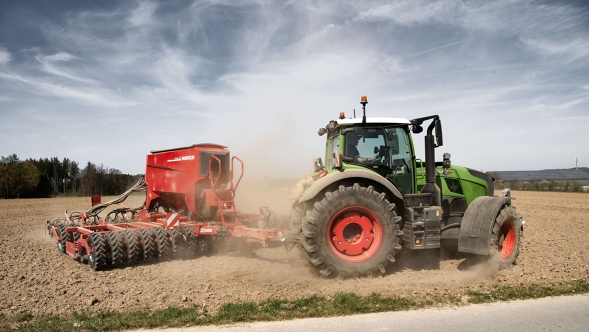Ein Fendt 700 Vario mit Ladewagen fährt im Sommer auf einer Landstraße