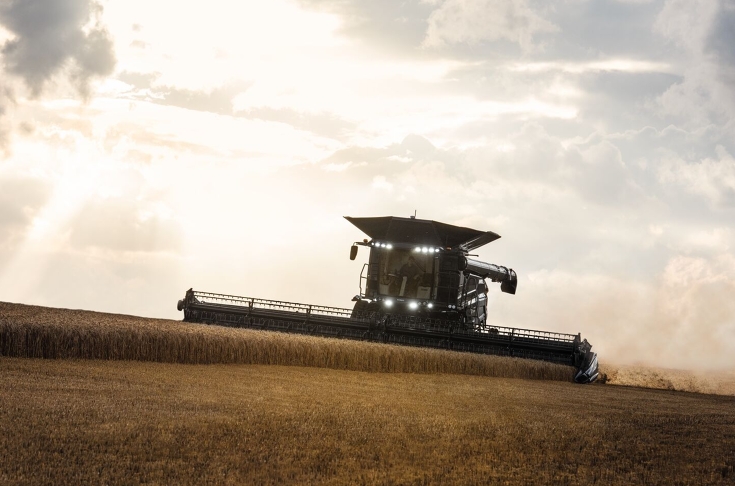 Fendt IDEAL im Getreidefeld Ein Fendt IDEAL Mähdrescher fährt frontal auf die Kamera zu und drischt Weizen im frühen Abend. Die Scheinwerfer sind angeschaltet.