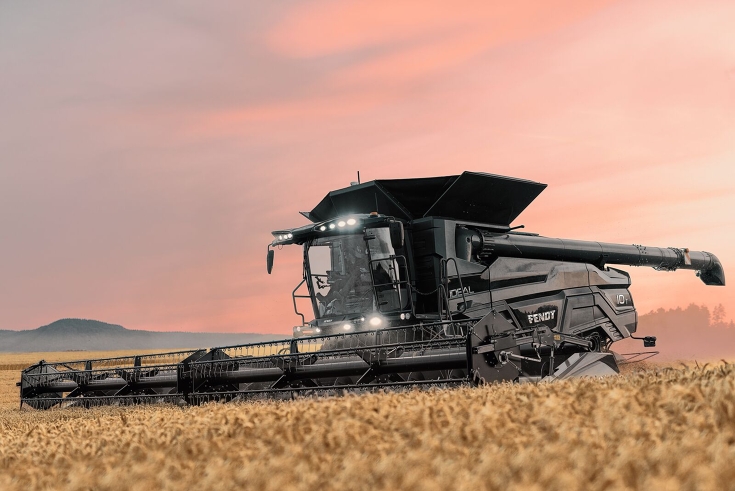 Getreideernte mit dem Fendt IDEAL Mähdrescher Ansicht auf einen schwarzen Fendt IDEAL Mähdrescher bei der Ernte im Getreidefeld mit eingeschalteten Scheinwerfern