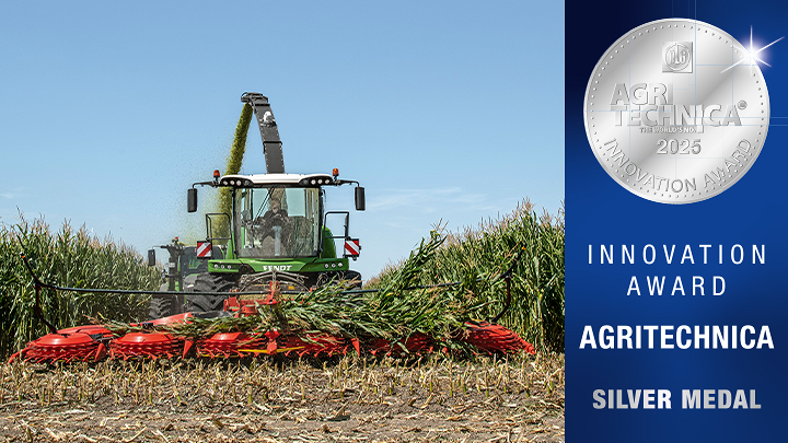 Der Katana Feldhäcksler im Feldeinsatz mit einem nebenstehenden Banner zur DLG Innovation Award Silbermedaile zur Agritechnica 2025