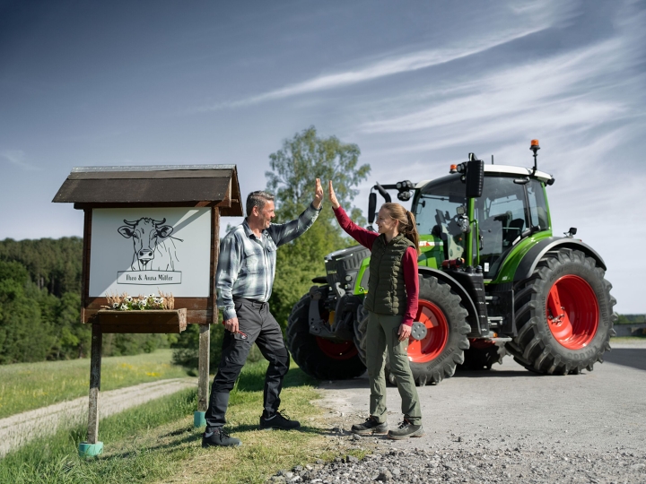 Kampagnenmotiv zum Fendt 500 Vario Gen4 Landwirt und Tochter stehen vor ihrem Hofschild mit ihrem Fendt 500 Vario Gen5 im Hintergrund