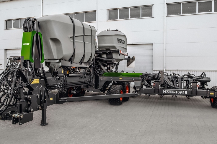 Die Fendt Sämaschine Fendt MOMENTUM steht auf einem Hof vor einer Halle.