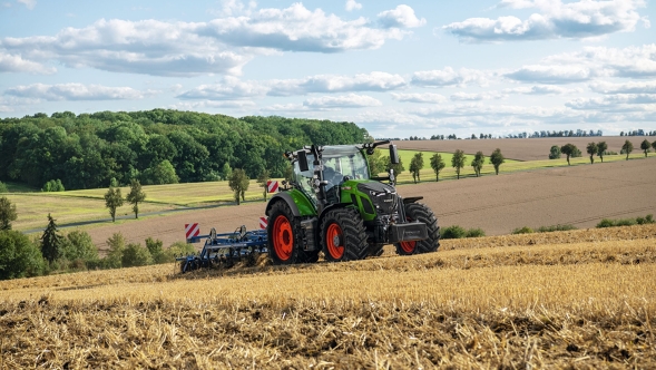 Fendt 600 Vario Ein grüner Fendt Traktor mit roten Felgen bei der Bodenbearbeitung auf einem abgeernteten Feld mit sanfter Hügellandschaft im Hintergrund
