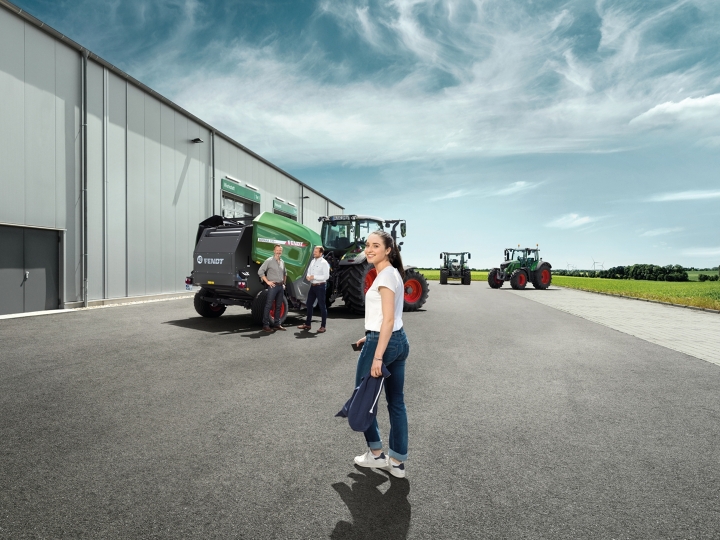 Kvinde i forgrunden, i baggrunden Fendt Rotana med traktorer ved udlevering til kunden