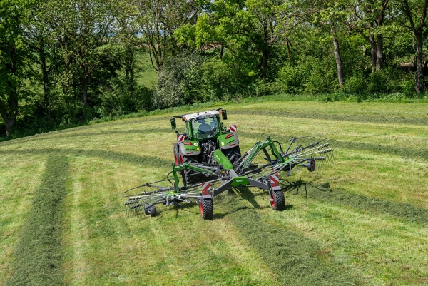 Fendt Former En Fendt-traktor kører med en Fendt Former-rive på en grøn mark.