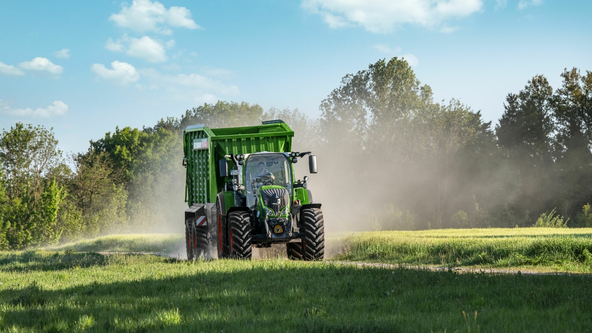 En Fendt 700 Vario Gen6 med monteret Tigo fodervogn på vej til marken.