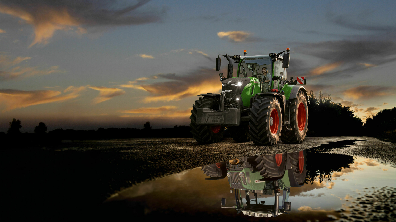 En Fendt 700 Vario Gen7 på en vej foran en smuk solnedgang  700 Vario Gen7