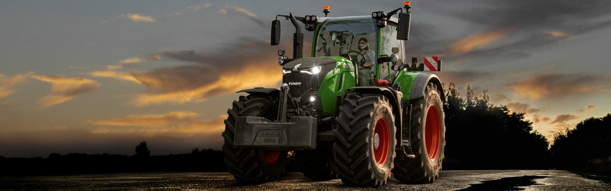 En Fendt 700 Vario Gen7 på en vej foran en smuk solnedgang