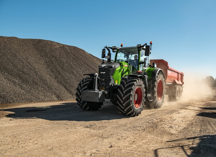 Fendt 728 Vario med anhænger på en byggeplads En Fendt 728 Vario kører forbi et bjerg af grus på en byggeplads med en rød container