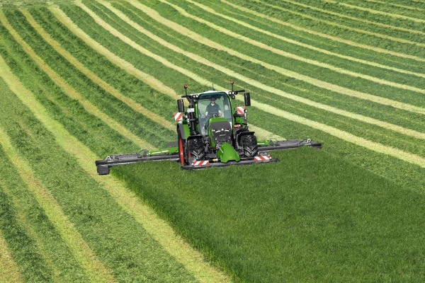 Fendt 600 Vario Den grønne Fendt 600 Vario traktor slår med det grønne redskab Fendt Slicer græs på en grøn eng, i baggrunden ses slåspor.