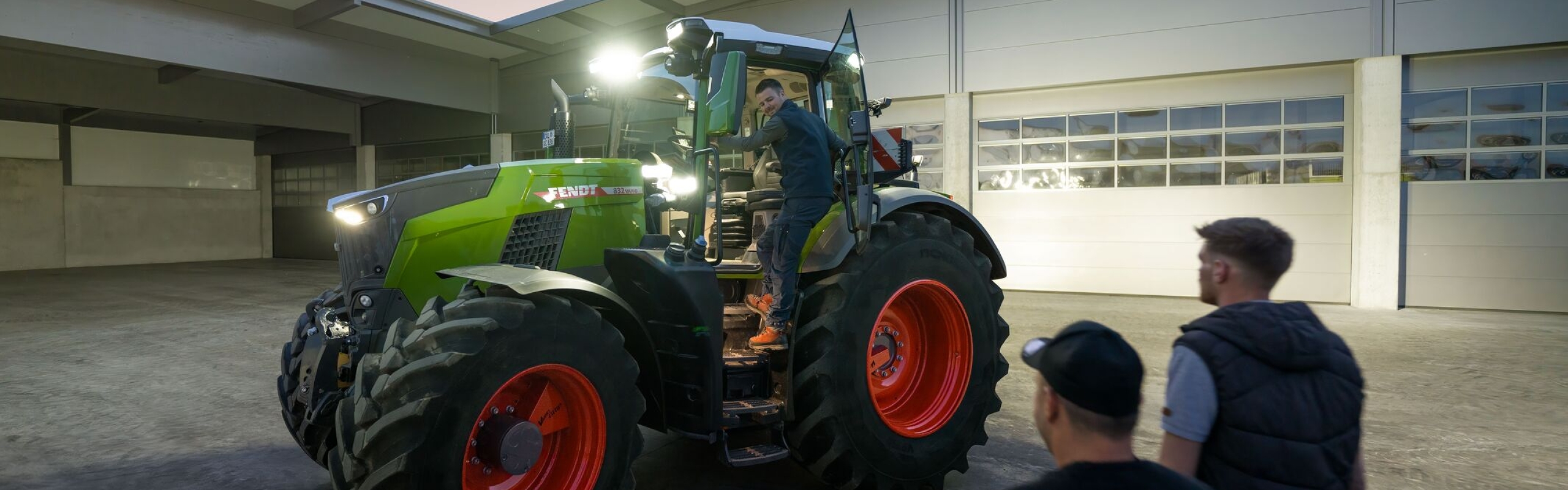 Et kig ind på gården hos en maskinstation, der har en Fendt 800 Vario traktor med fuld belysning klar til sin fører.