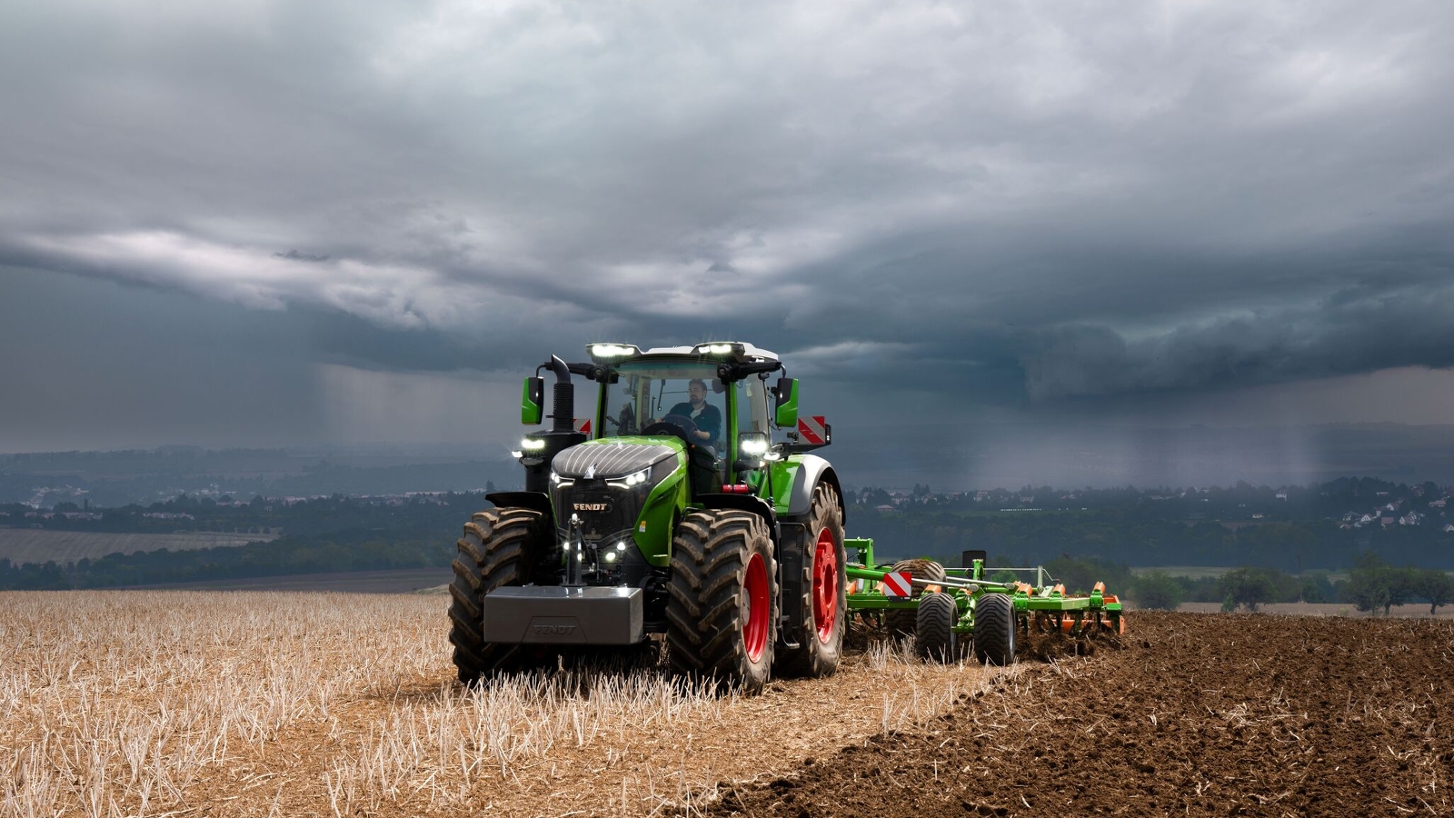 Med de tunge tordenskyer i det fjerne, klarer Fendt 1000 Vario traktoren sit arbejde i marken med rigelige kræfter.