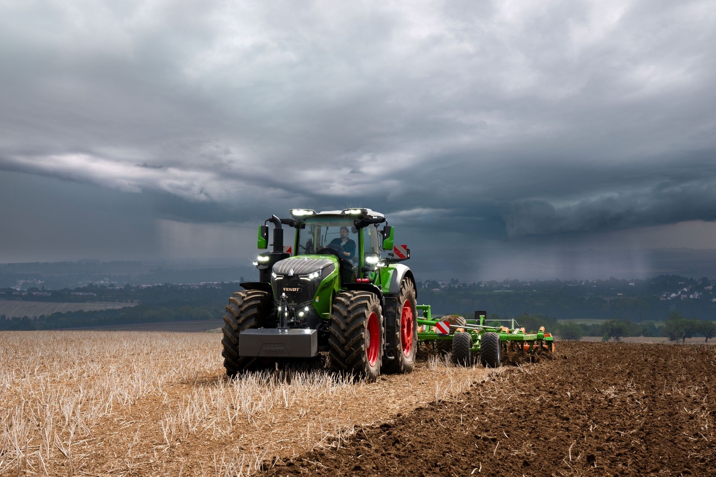 Med de tunge tordenskyer i det fjerne, klarer Fendt 1000 Vario traktoren sit arbejde i marken med rigelige kræfter.