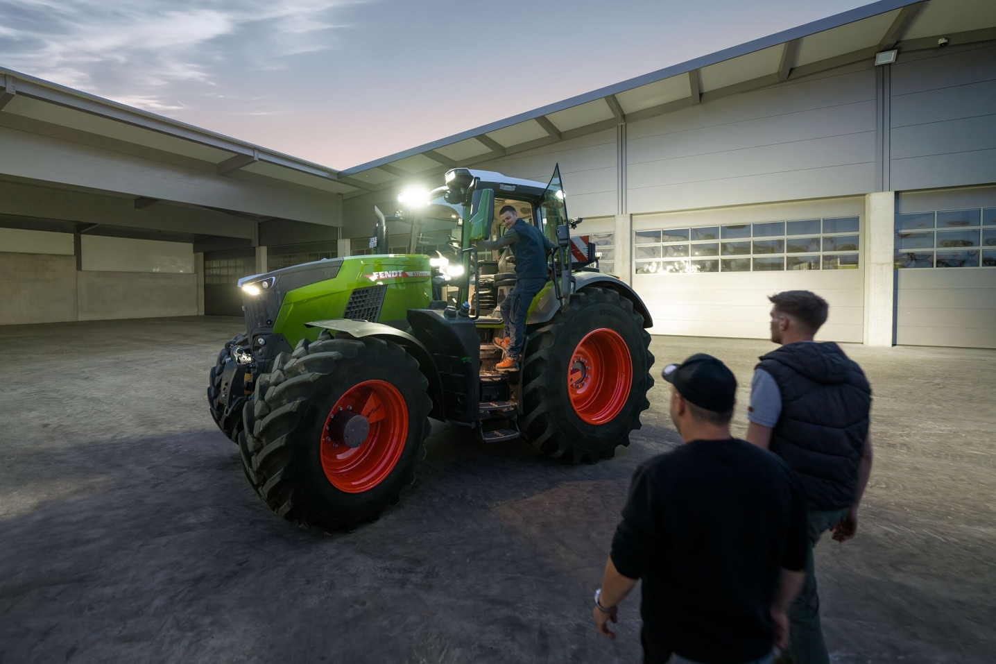 Et kig ind på gården hos en maskinstation, der har en Fendt 800 Vario traktor med fuld belysning klar til sin fører.
