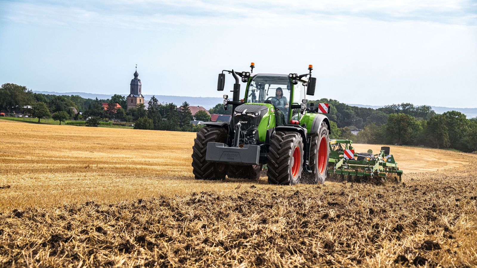 Fendt 700 Vario Gen7 En kvinde kører i marken med en Fendt 700 Vario Gen7 og en harve.