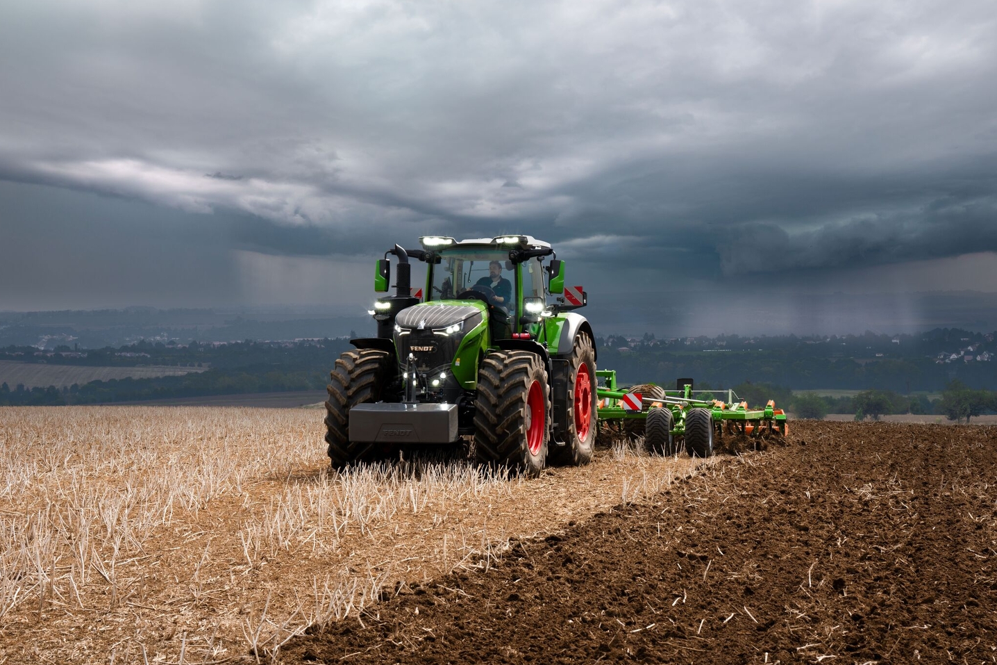 Fendt 1000 Vario traktor teeb endiselt võimsalt oma põllutööd raskete, kaugel ähvardavate tormipilvede ees