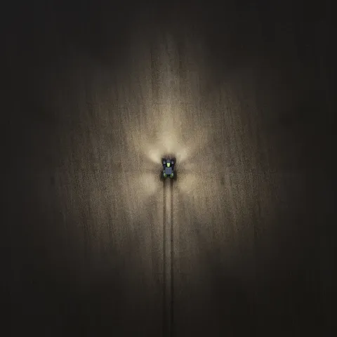 Imagen de dron de un Fendt 800 Vario de noche con las luces encendidas – 60%.