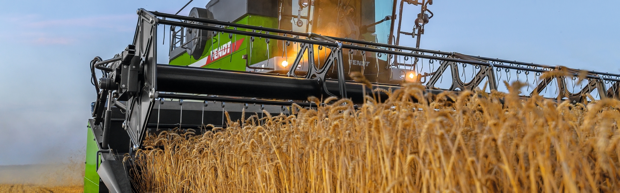 Un agricultor trillando con su cosechadora Fendt CORUS al anochecer.