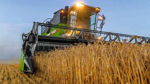 Un agricultor trillando con su cosechadora Fendt CORUS al anochecer.