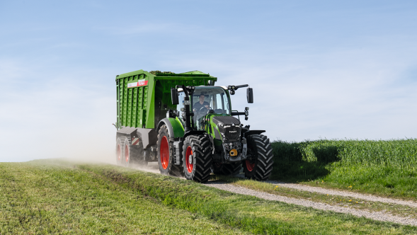 Una Fendt 600 Vario con un remolque autocargador Fendt Tigo circulando por un camino sin asfaltar