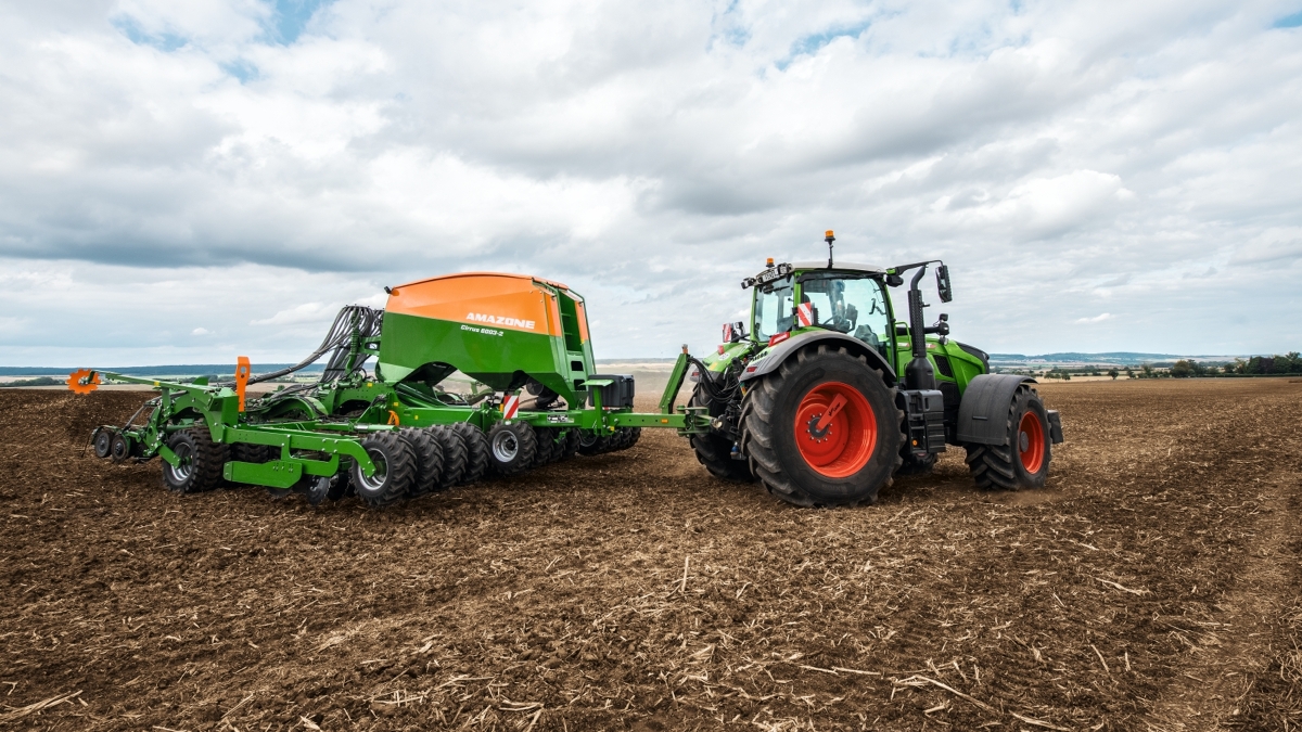 Una agricultora conduce por el campo un Fendt 700 Vario Gen7 con una trilladora Amazone.