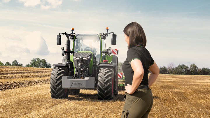 Una agricultora está delante de su Fendt 700 Vario Gen7 en un campo de rastrojos.