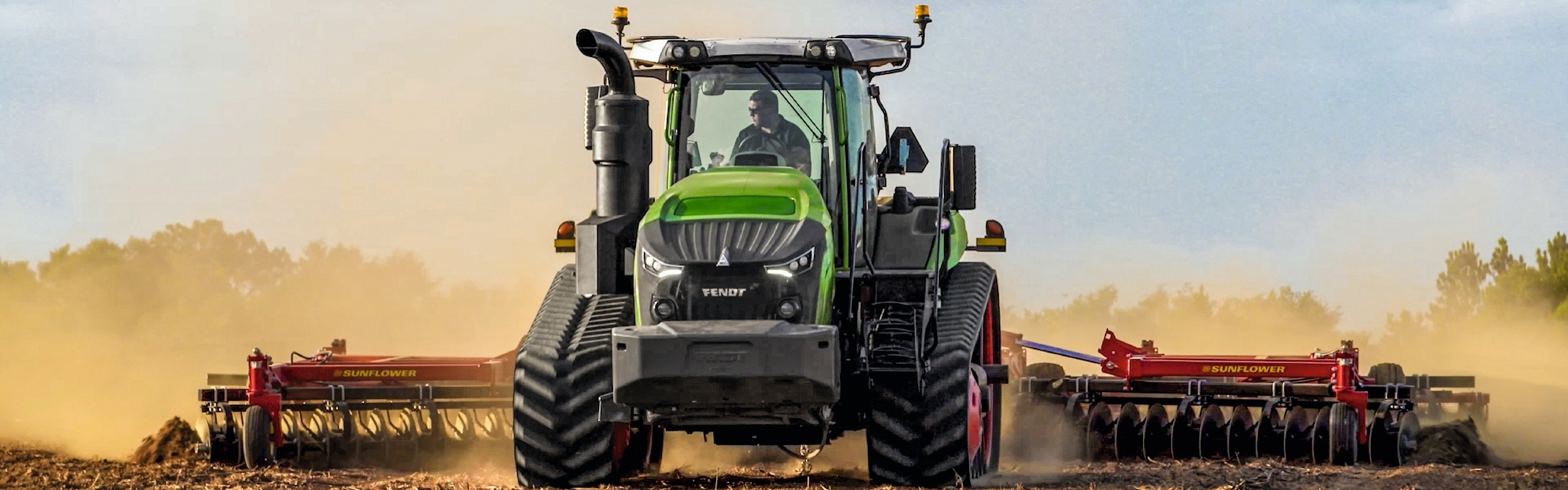 Un agricultor conduce por un campo polvoriento un tractor de orugas Fendt 1100 Vario MT.