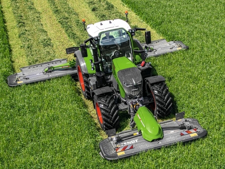 Un agricultor conduce un Fendt 700 Vario y siega el prado con un accesorio delantero y trasero Fendt Slicer.