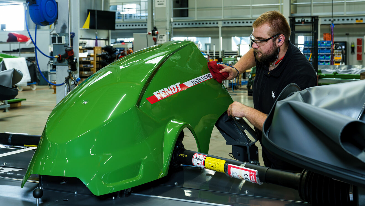 Un empleado de Fendt monta algo en el capó de una Fendt Slicer.