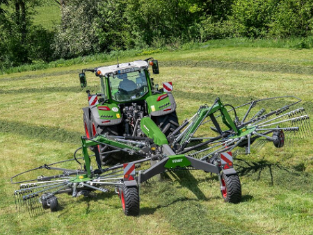 Un tractor Fendt circula con un rastrillo Fendt Former por un campo verde.