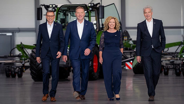 Walter Wagner, Christoph Gröblinghoff, Ingrid Bußjäger-Martin y Ekkehart Gläser sonríen uno al lado del otro en el Fendt Forum delante de un tractor Fendt