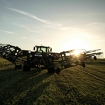 Un tractor Fendt verde con Fendt Former 14055 PRO circula por el campo durante el atardecer