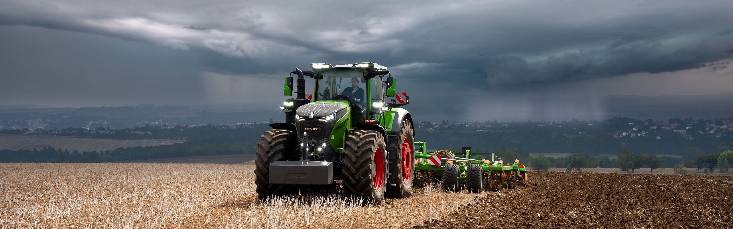 El tractor Fendt 1000 Vario sigue realizando con brío su trabajo en el campo frente a las pesadas nubes de tormenta que se ciernen a lo lejos