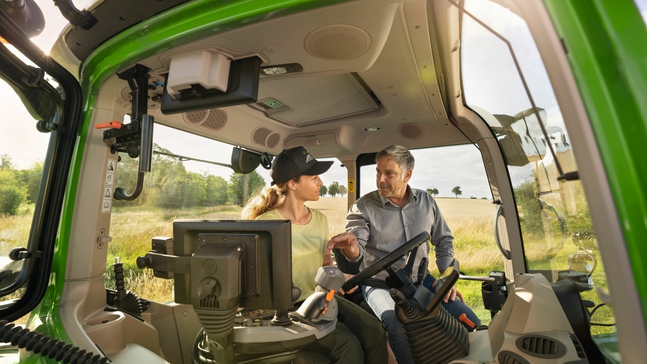Un distribuidor Fendt en la cabina de un tractor verde, un modelo de demostración del Fendt 700 Vario Gen7 en la explotación de una cliente.